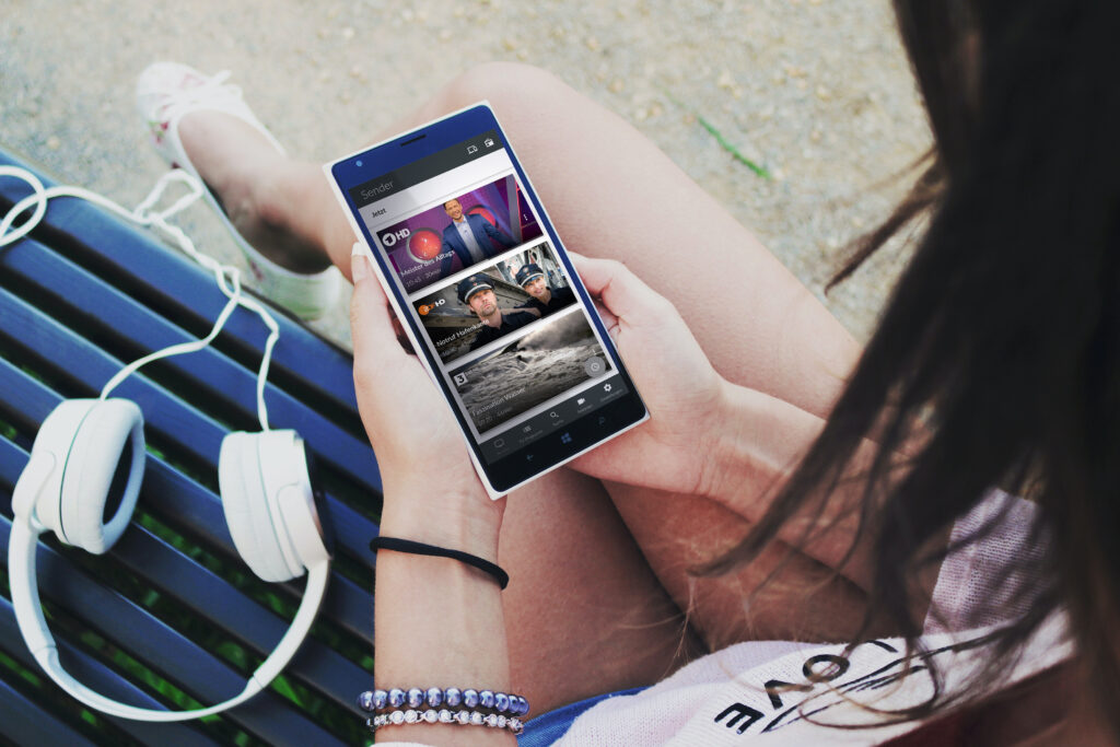 Frau die sich auf ihrem Handy das Fernsehprogramm ansieht